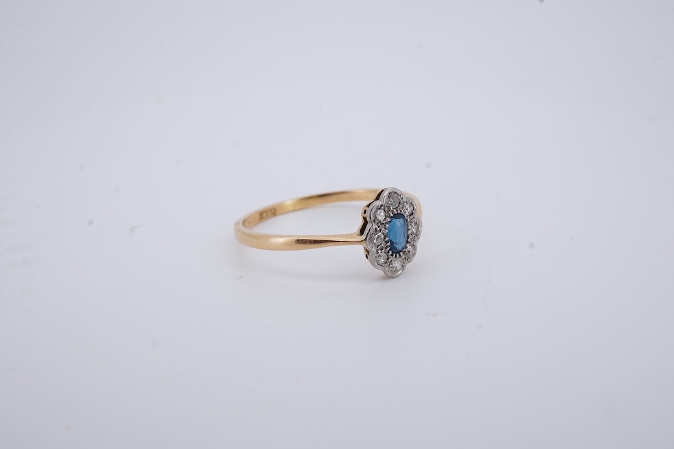 A 1920's yellow metal, stamped 18ct, sapphire and diamond set oval cluster ring, size V, gross weight 2.3 grams. Condition - poor to fair